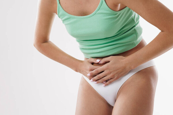Woman suffering from abdominal pain, menstrual cramps, stomachache, PMS discomfort, digestion issues, or bloating, holding stomach in pain.