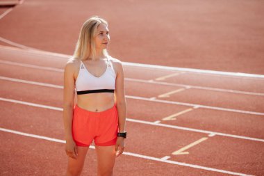 Koşu pistinde başlangıç çizgisinde koşan bayan atlet, bir sprint için hazırlanıyor, odaklanmış ve yarış yarışması ve zirve performansı için kararlı