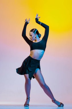Siyah kıyafetli şık bayan dansçı Latin dansında canlı gradyan stüdyo arka planında hareket ediyor..
