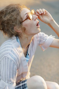 konsept görme bozukluğu, çilli genç bir kadın büyük vintage gözlük takıyor kameraya tuhaf bir şekilde bakıyor örgü kazak ve kareli elbiseler giyiyor..