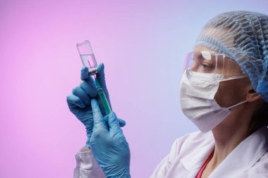 Koruyucu maskeli kadın doktor ve eldivenler şırıngayı cam şişeden aşıyla dolduruyor, tıbbi enjeksiyon hazırlığı. Modern tıp kavramı