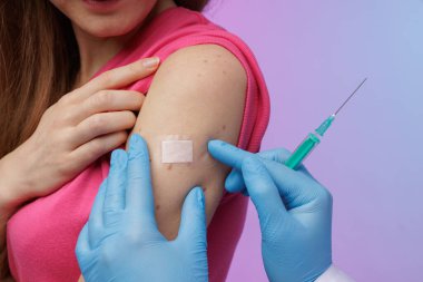 Aşı sonrası bandaj uygulayan bir sağlık uzmanının elinde şırınga, iğne sonrası bakım ve hastanın güvenliğini sağlarken yakın plan çekimi..