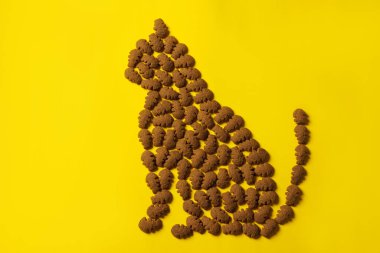 Kedi şeklindeki desen canlı sarı arka planda canlı bir evcil hayvan ürününden yapılmış kedi beslenmesini, yaratıcılığı ve evcil hayvan bakımı kavramlarını sembolize ediyor..