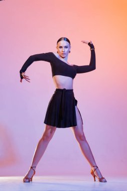 Siyah kıyafetli kendinden emin bir bayan dansçı canlı stüdyo ışıkları altında dinamik bir duruş sergiliyor dans konsepti, dersler, okul...