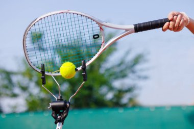 Tenis raketinin yakın plan görüntüsü antrenman aleti ile topa vurmak, güneşli bir günde açık hava antrenmanı..