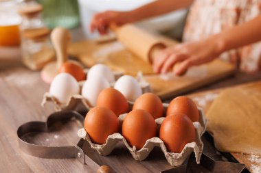 Kutudaki kahverengi ve beyaz yumurtaların yakın plan çekimi. Samimi mutfakta yuvarlanan çocuk hamuru. Hazırlık sahnesi..