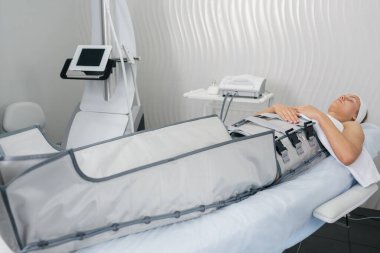 Kadın, modern bir sağlık kliniğinde vücut inceltme ve lenfatik drenaj tedavisi görüyor..