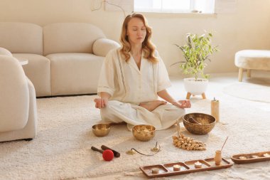 Tibet ses kaseleri, tütsü ve mumlarla huzur içinde meditasyon yapan bir kadın..