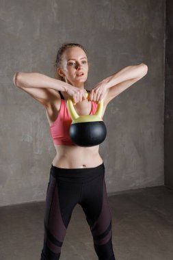 Dayanıklılık, güç ve üst vücut kondisyonuna odaklanan, dayanıklılık antrenmanı sırasında kettlebell kaldıran formda bir kadın..