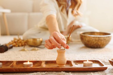 Kadın tütsü yakıyor, mumlar ve meditasyon ve enerji temizliği için Tibet kâseleri kullanıyor..