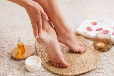 Havluyla çevrili kadınlar ayak bakımı için kozmetik ürünler, fırça, krem ve yağ kullanıyor. Kişisel bakım, kaplıca ve cilt sağlığı konsepti.