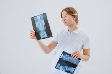 Kadın rehabilitasyon uzmanı omurga eğriliği, kırıklar, yer değiştirme ya da omurga sorunları için omurilik röntgenlerini inceliyor.