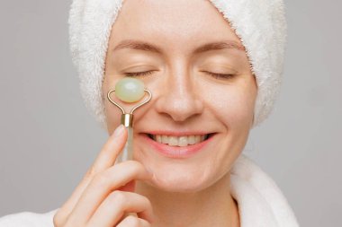 Mutlu kadının havluyla yüz masajı, kırışıklık giderme ve kaplıcada cilt bakımı yaptığı yakın plan..