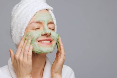 Kafasında havlu olan mutlu kadın yeşil oksijen uyguluyor köpük yüz maskesi ışıl ışıl, sağlıklı ve tazelenmiş cilt spa.