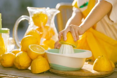 Çocuk meyve sıkacağı ile limon sıkıyor, sağlıklı bir yaz içeceği için taze narenciye suyu yapıyor, parlak ve doğal ışık..