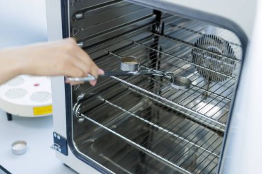 Bilim insanları örnekleri analiz, kalite kontrolü ve bilim ve endüstri laboratuvarlarında araştırma için laboratuvar fırınına yerleştiriyor..