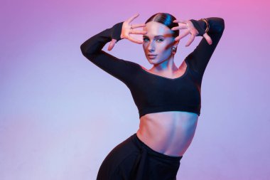 Siyahlı, etkileyici el pozuyla kendine güvenen Latin dansçıya yaklaş. Stüdyoda modern, şık ve sanatsal portre.