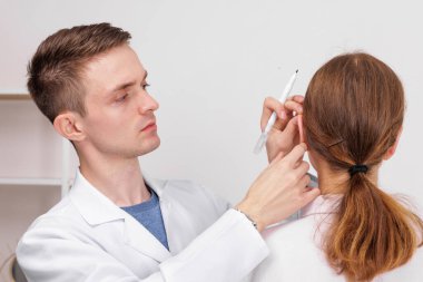 Ototlasti estetik ameliyatından önce kulağını işaretleyen doktor. Tıbbi danışma, düzeltme ve ameliyat öncesi hazırlık.