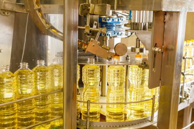 Temiz şişeler ve gelişmiş şişeleme makineleriyle modern bir fabrikada otomatik ayçiçeği yağı üretim hattı