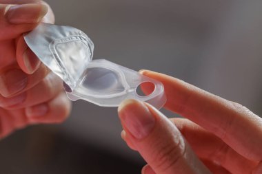 Günlük görme düzeltmesi ve kırılma hatası çözümü için steril lens kabartma paketini açan elleri kapatın