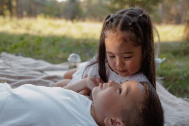 Erkek ve kız kardeş yaz pikniği sırasında birlikte dinleniyorlar. Aile bağları ve doğada şefkat.