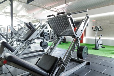 Bacak pres makinesi ve fitness, vücut geliştirme ve sağlıklı yaşam tarzı için güçlü eğitim ekipmanlarıyla modern spor salonu.