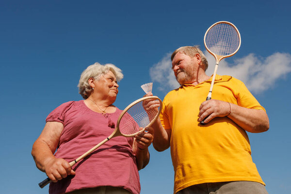 Happy senior couple enjoying badminton and outdoor activity together, promoting wellness and active aging lifestyle