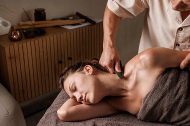 Terapist boyun ve omuza gua sha bıçak masajı yapar kas gevşemesi, gerilim ve derin rahatlama için.