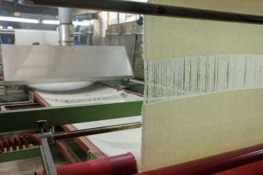 Tekstil fabrikasında dokuma makinesi olan yün kumaş üretim hattı, endüstriyel süreci ve giysi imalatı için iplikleri gösteriyor.