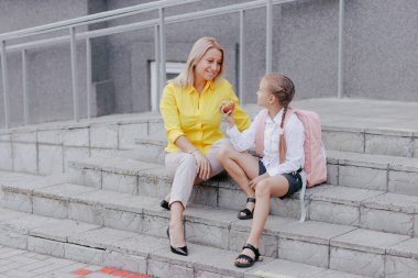 Anne ve kızı okuldan önce okul merdivenlerinde sağlıklı bir atıştırmalık yiyorlar. Okula dönüşün ilk gününü kutluyorlar..