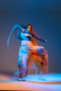 Enerjik caz funk dansçısı canlı ışıklandırma ile dinamik hareket gösteriyor, modern dansın tutkusunu ve yaratıcılığını yakalıyor..