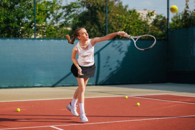Odaklanmış genç kadın tenis topunu açık hava antrenmanı sırasında sahada servis ediyor. Güç, eylem ve motivasyonu gösteriyor.