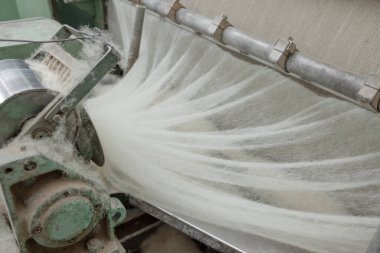 Bir tekstil değirmeninin içindeki ince dilimli ve iplik üretimine doğru giden bir varilden alınan yün ağ taslakları, temiz doğal fiber işlemeyi gösteriyor..