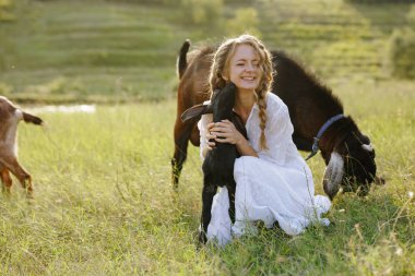 Yeşil çayırda çocuğu olan mutlu kadın çiftçi keçi sütü peyniri organik tarım ve kırsal hayat hikayeleri için mükemmel.