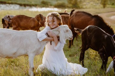 Mutlu çiftçi çayırda keçiyi kucaklıyor keçi sütü peyniri, organik süt, kırsal yaşam tarzı ve hayvan refahı hikayeleri için otantik görsel