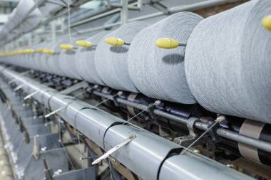 Large yarn rolls feed a warping line in a textile factory showing automation precision workflow and quality manufacturing