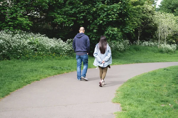 A multicultural couple walking on a footpath in Figgate Park in Edinburgh in spring time. Multiethnic family.