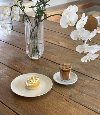 Masanın üzerinde bir fincan kahve ve çiçek var.