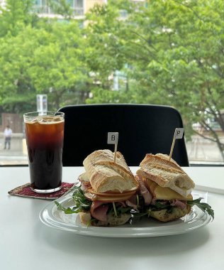 Peynirli sandviç, domates ve salata beyaz masada.