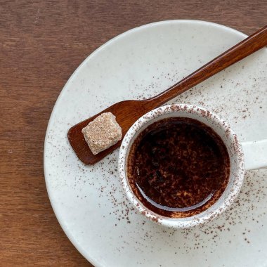 Bir fincan espresso ve tahta bir masa üzerinde kaşık.