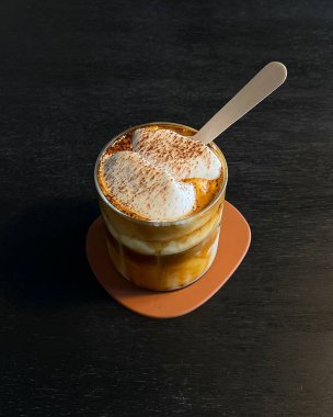 Dikey seçmeli, siyah arka planda beyaz fincan ve çikolatalı lezzetli bir tatlının fotoğrafı.