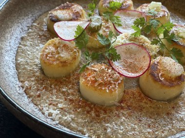 Kızarmış deniz taraklarını otlarla kaplayın.