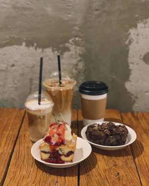 Bir fincan kahve, bir kek ve siyah bir masada bir fincan çay.