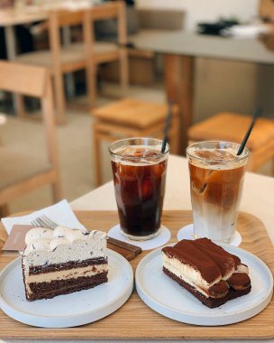 Kahve fincanı, krema ve kek ile ahşap bir masada.