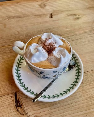 Kahveli fincan ve masada köpüklü kapuçino.