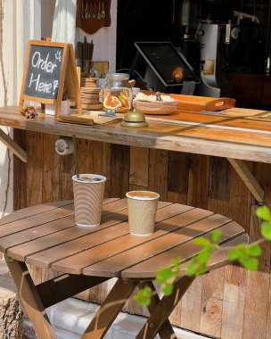 Bahçedeki bir masanın arka planında bir bardak çay olan ahşap bir tepsi.