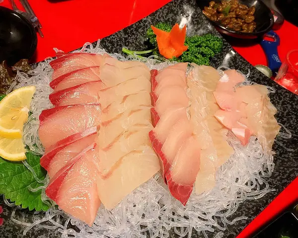 Çiğ taze balık, sebzeli, otlu ve siyah tabakta baharatlı.