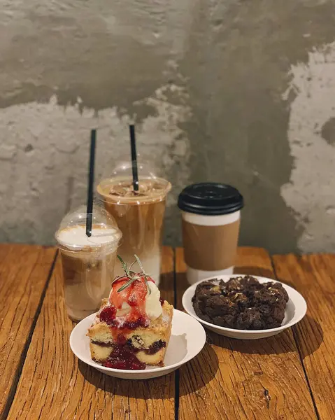 Bir fincan kahve, bir kek ve siyah bir masada bir fincan çay.