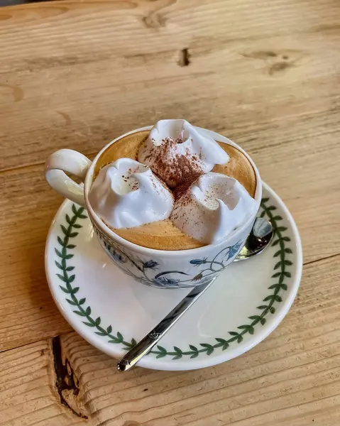 Kahveli fincan ve masada köpüklü kapuçino.