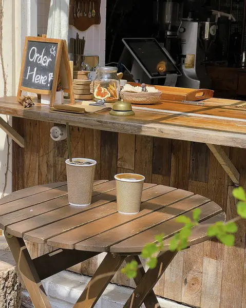 Bahçedeki bir masanın arka planında bir bardak çay olan ahşap bir tepsi.